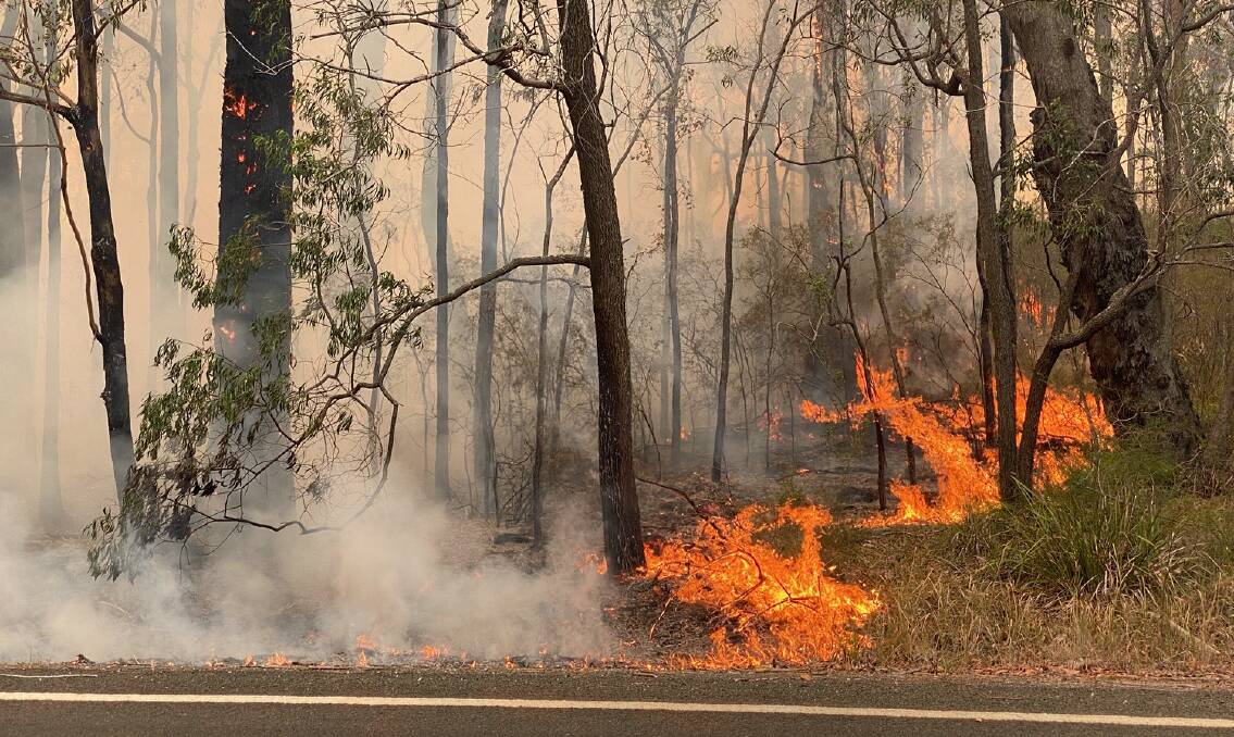 Fires continued to burn on the Princes Highway north of Batemans Bay on Tuesday. Picture: Stuart Thomson