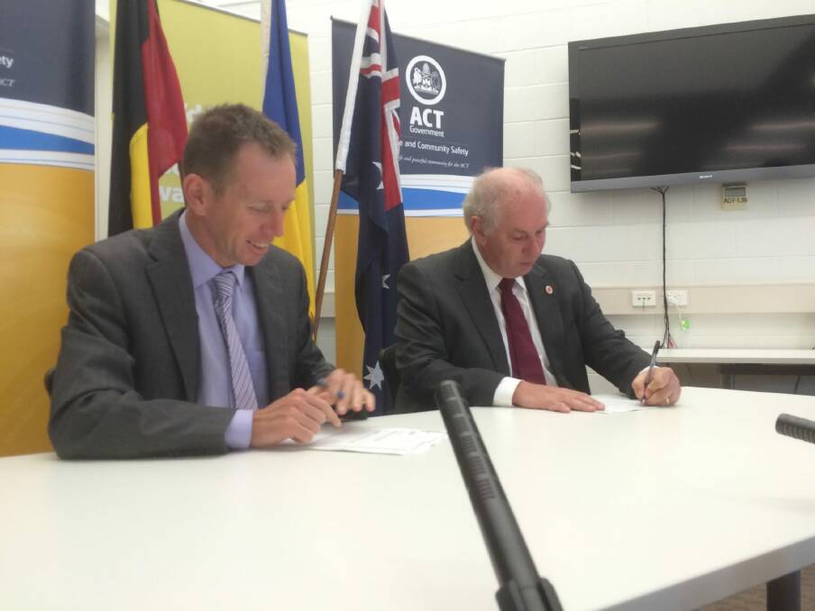 Justice Minister Shane Rattenbury signs the deed of agreement with Community and Public Sector Union national president Alistair Waters.