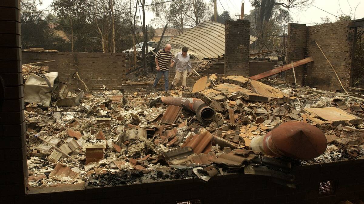 Residents in Duffy walk through the rubble of their home the day after the January 18 firestorm in 2003. Photo: Graham Tidy.