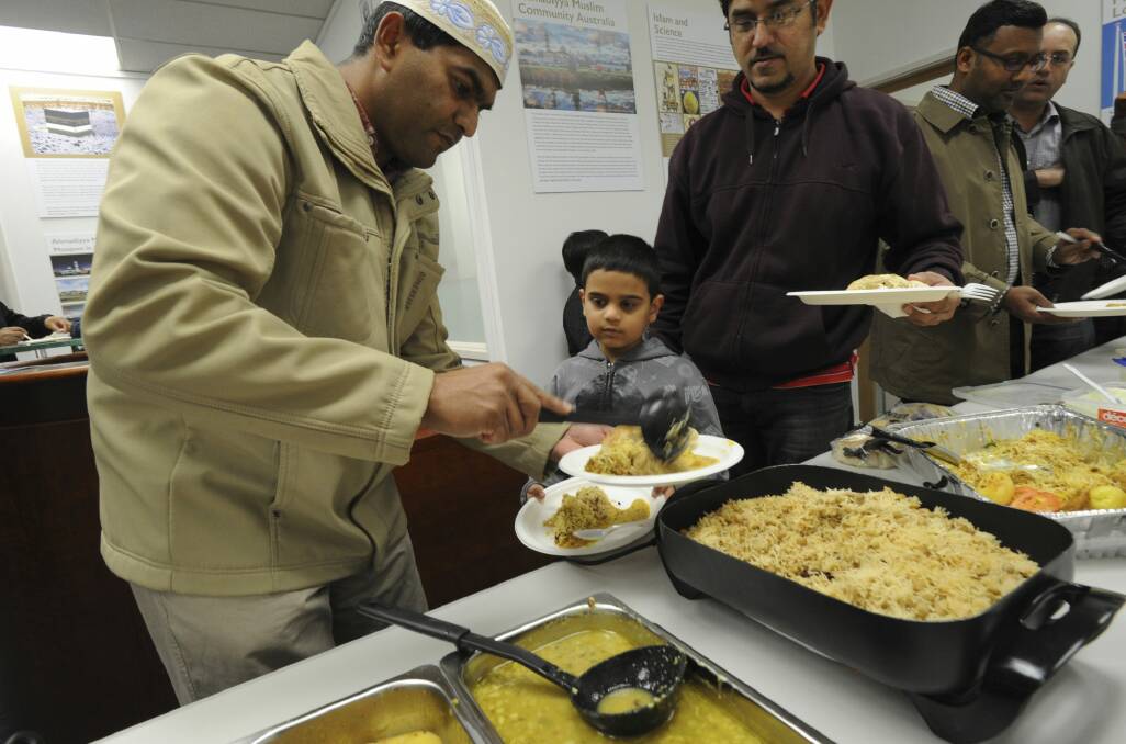 Rahimat Ali feeds son  Rehan, 7, at the breaking of the fast for Ramadan at the Ahmadiyya Muslim Association Canberra branch in Fyshwick. Photo: Graham Tidy