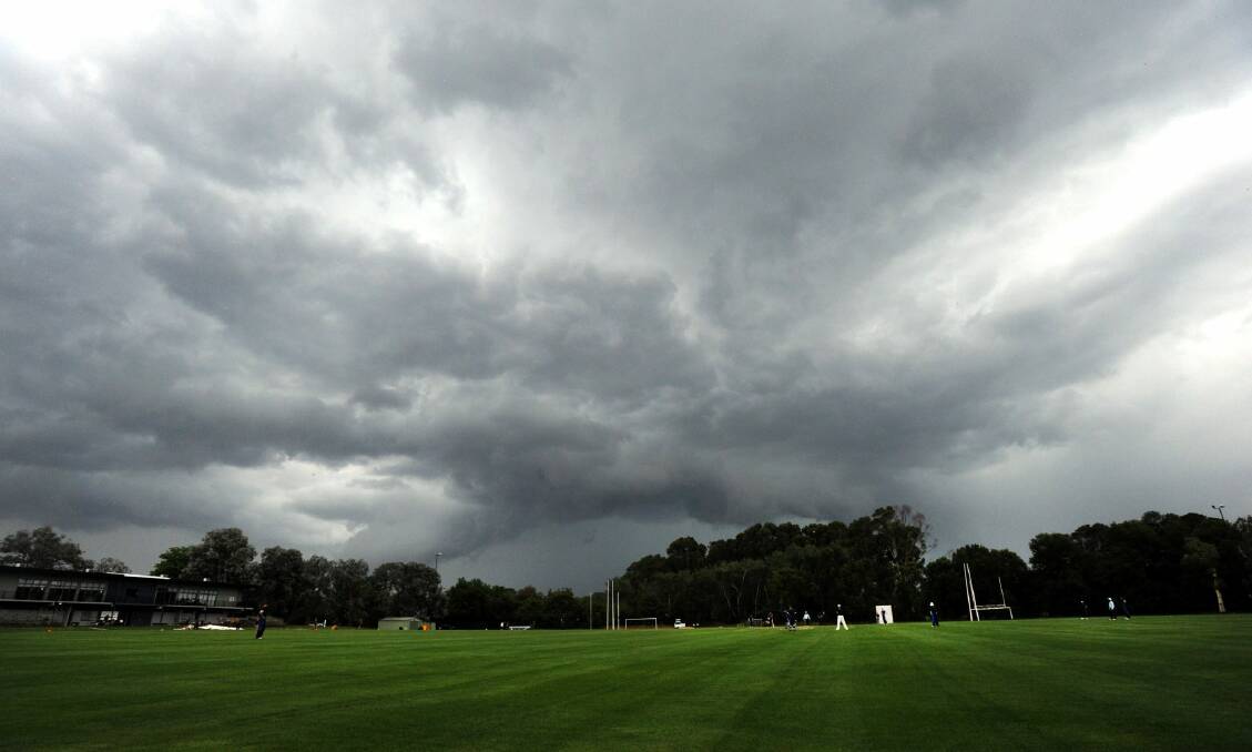 Dark clouds loom on ANU North Oval before it pelted down with rain on Saturday.  Photo: Graham Tidy.