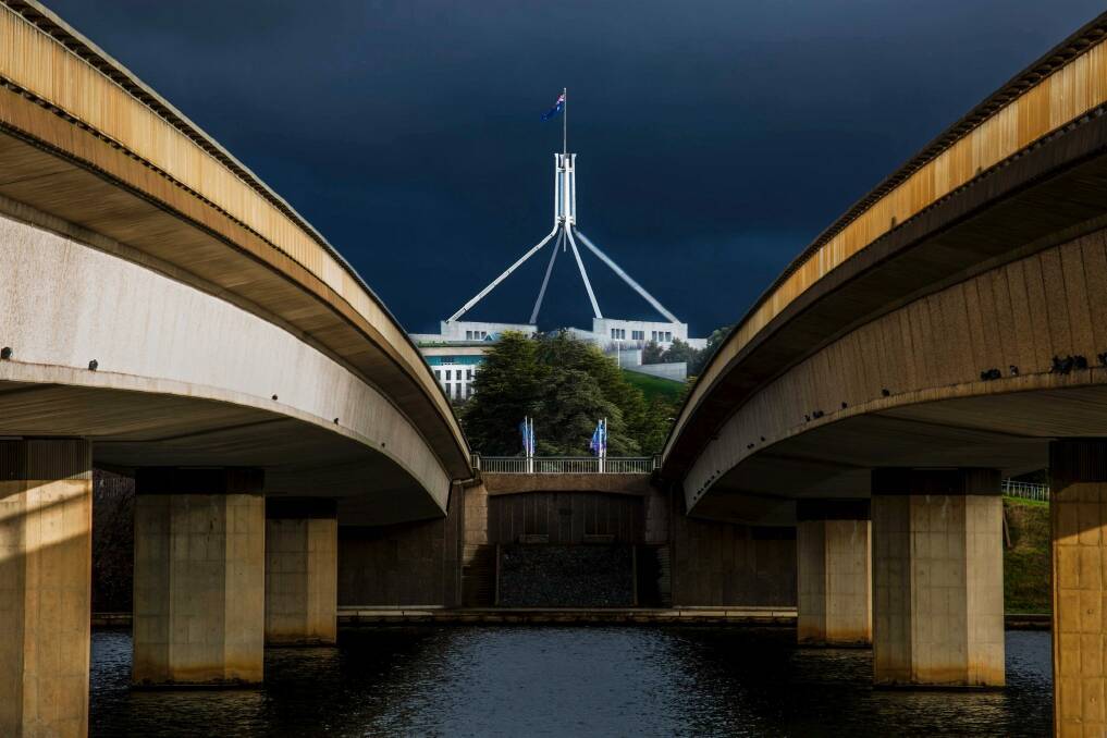 Parliament House, as seen through Commonwealth Bridge. The Barr government is considering building a bridge in between to get light rail over the lake.  Photo: Grant Phillips