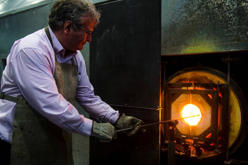 <i>Canberra Times</i> reporter Ron Cerabona under the supervision of Make Your Own instructor Nick Adams, heats what will be a glass tumbler at Canberra Glassworks.  Photo: Sitthixay Ditthavong