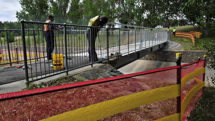 A new footbridge over a stormwater drain in Curtin has the final touches put on it by workers. Photo: Jay Cronan