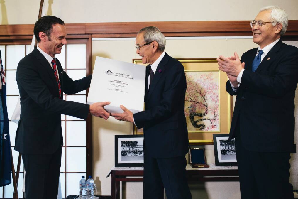 Director-General of the National Archives of Australia David Fricker hands over a box of records to president of the National Archives of Japan Takeo Kato as ambassador Sumio Kusaka watches on. Photo: Rohan Thomson