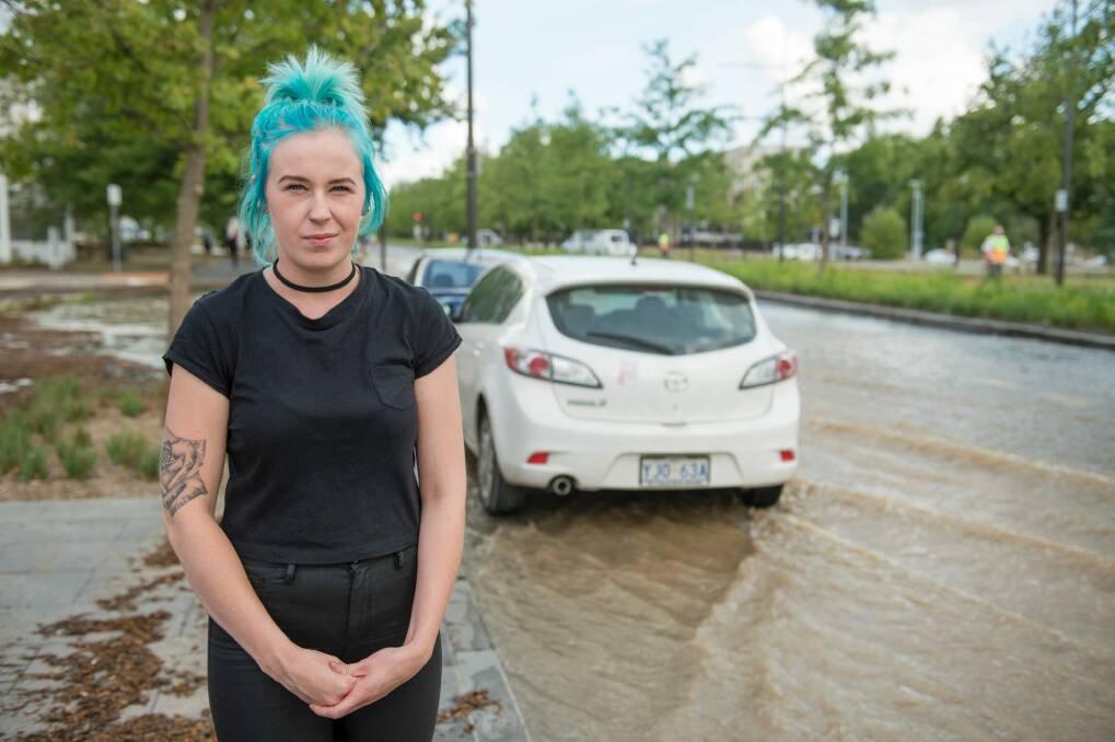 Rhiannon Walker watches as water swamps her car after a water main bursts on Constitution Ave in Canberra. Photo: Jay Cronan