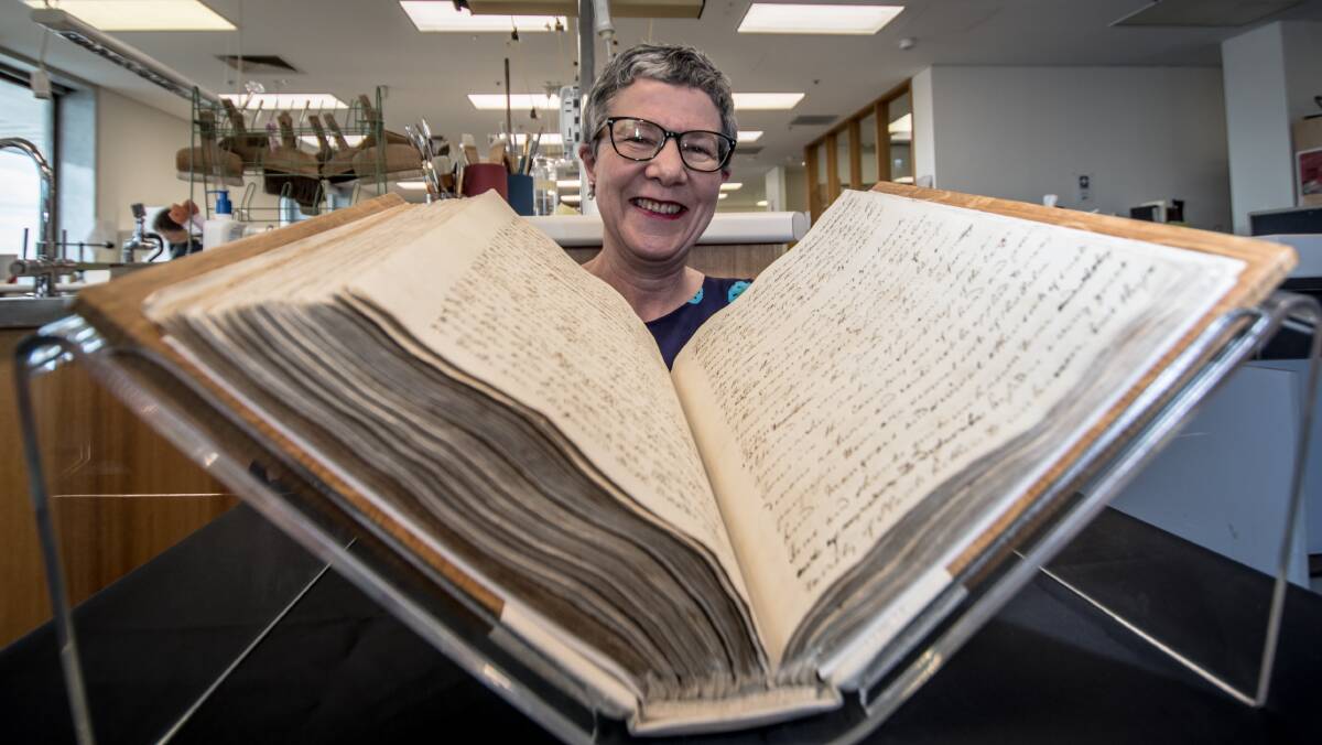 Director-General of the National Library of Australia, Dr Marie-Louise Ayres, pictured with the 250 year old captain's log from the Endeavour sailing.  Photo: Karleen Minney