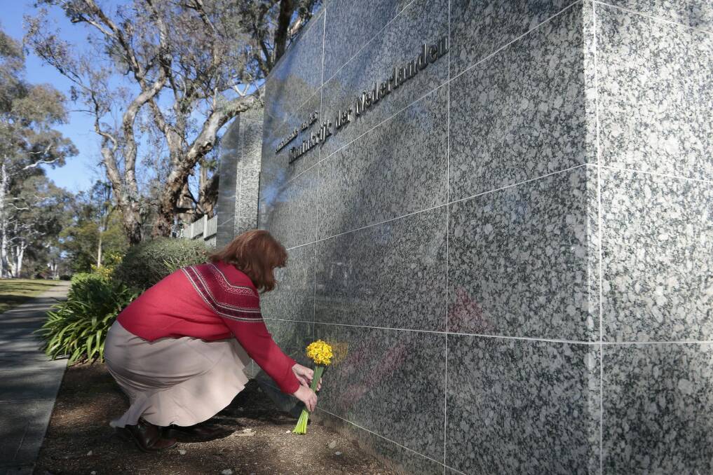 Angela Clifford places flowers outside the Netherlands embassy. Photo: Jeffrey Chan