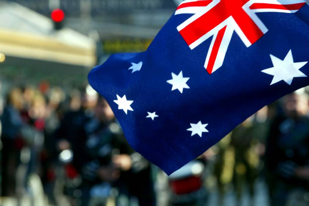 Crowd members wave an Australian flag as marchers go past on Swanston St during the ANZAC day march in Melbourne 2003.