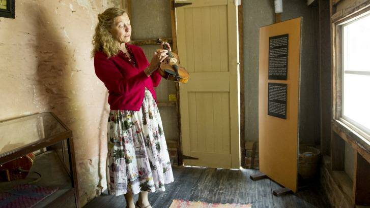 Jenny Gall inspects the violin of the Mugga Mugga Homestead. Photo: Jay Cronan
