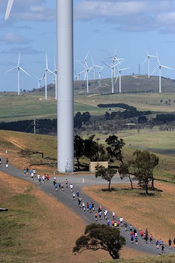 Runners pass one of the towers at the "Run with the Wind" fun run at the Woodlawn Wind Farm, near Bungendore. Photo: Graham Tidy