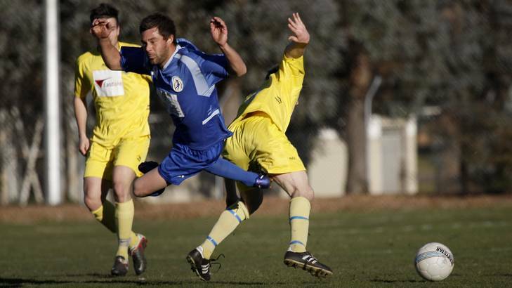 Canberra Olympic's Robbie Deeley gets fouled by Canberra City's Jonathan Bills. Photo: Jeffrey Chan