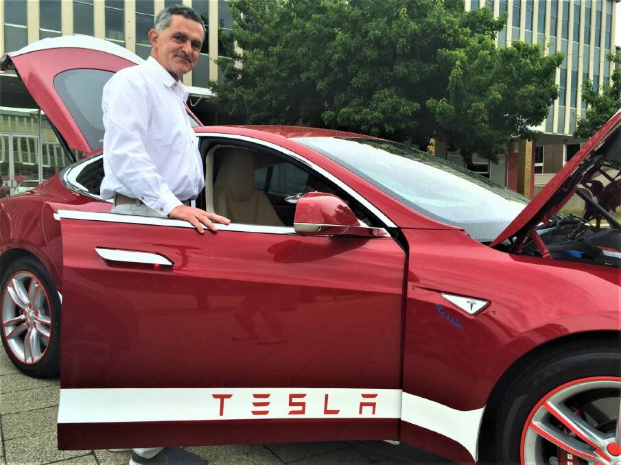 Rene Konrad with charges his Tesla electric car at home with energy from his solar panels. Photo: Katie Burgess