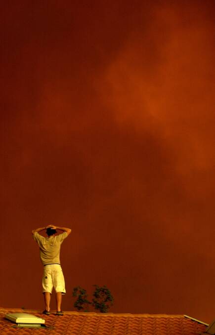 A residents watches the approaching red smoke from fires at Tharwa in 2003. Photo: Lannon Harley