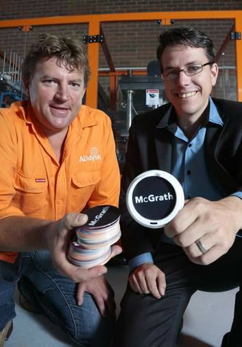 ADdysk managing director Dean Groening shows one of his clients McGrath Estate Agents director Chris Dixon a sample of his small advertising disk that will be placed on top of coffee lids at his factory in Mitchell. Photo: Jeffrey Chan