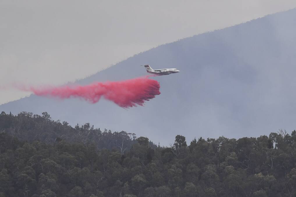 A water bombing airplane is seen dropping fire retardant at the Pierces Creek fire near Canberra in November. Photo: AAP