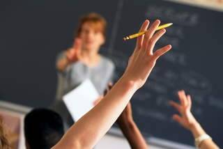 Teacher pointing to raised hands in classroom boarding school  Generic Photo: Supplied