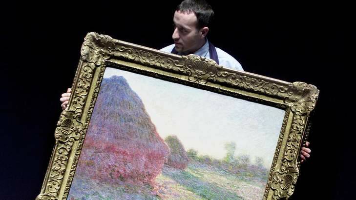 Sotheby's senior technician Dominic Cacioppo holds Claude Monet's painting, "Haystacks, last rays of the sun". Photo: Ian Waldie