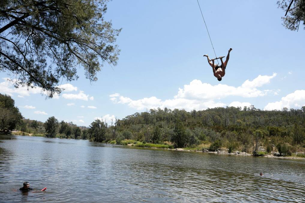 Joel Patton, of Woden, swings over the Murrumbidgee River as he tries to cool off in January. Photo: Jeffrey Chan