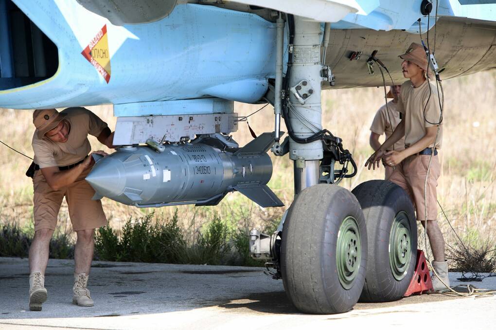Russian military support crew attach a satellite-guided bomb to a jet fighter in Syria. Photo: AP