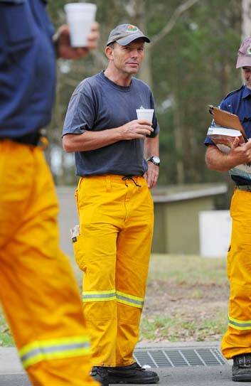 Volunteer &#8230; opposition leader, Tony Abbott, listens to a bushfire briefing. Photo: Greg Wood