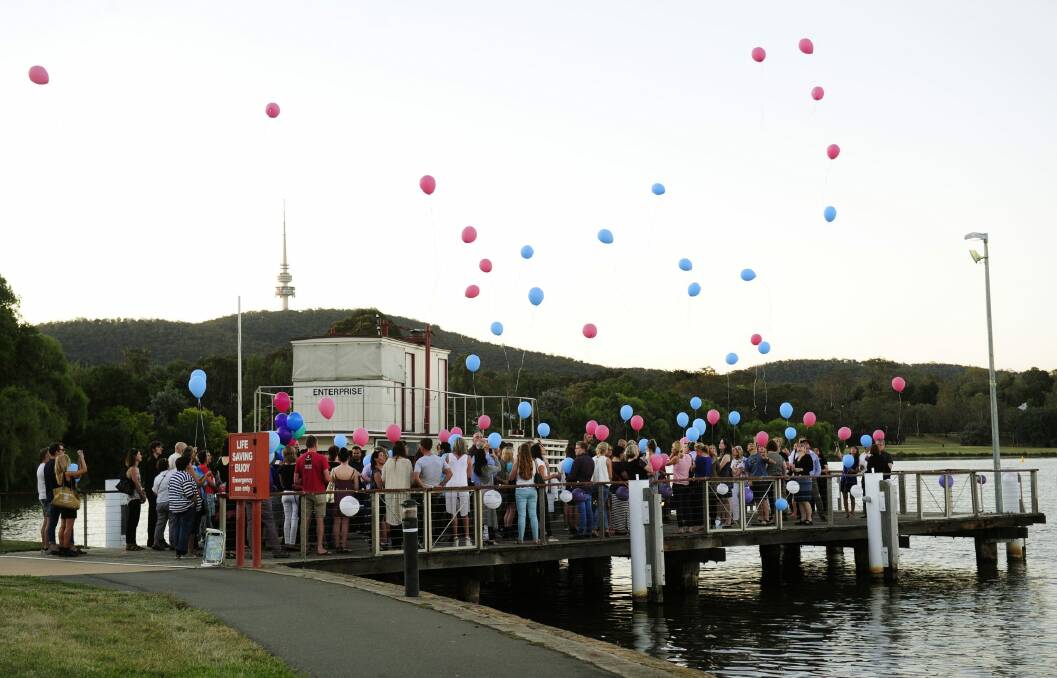 Family and friends release balloons from the jetty near the National Museum of Australia to pay their respects to Cathy Marsh, who died in a car accident. Photo: Melissa Adams
