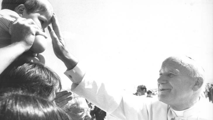The visit of Pope John Paul II at the RAAF Base Fairbairn in 1986 ... Pope John Paul II blesses a young boy as he meets the people at RAAF Base Fairbairn. Photo: Supplied