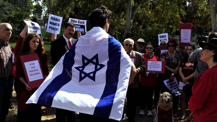 University student Noey Kolt, 20, addresses the rally outside the Israeli embassy as Labor MP Mike Kelly watches on. Photo: Jay Cronan