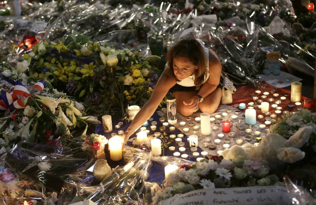 A woman lights candles at a memorial for the victims of the Bastille Day attack in Nice. Photo: AP