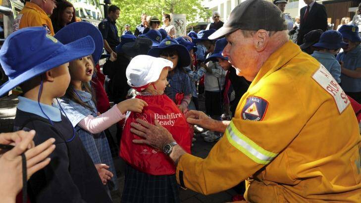 Tony Kidney, of the ACT Rural Fire Service, hands out Bushfire Ready information bags to Ainslie Primary School students. Photo: Graham Tidy
