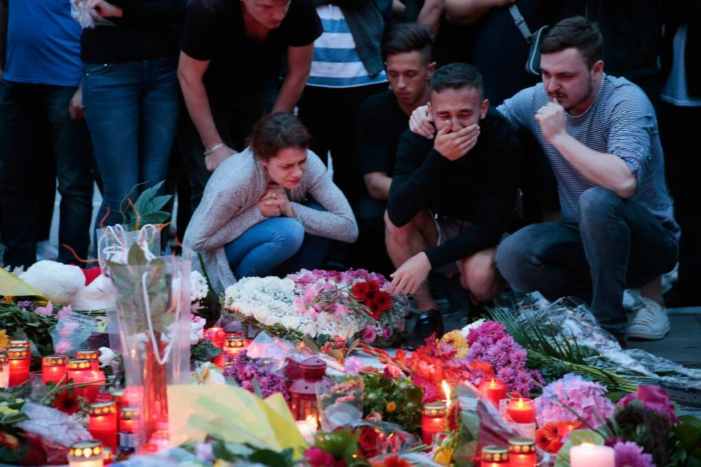 People mourn near the crime scene at OEZ shopping centre the day after a shooting spree left nine victims dead. Photo: Getty Images