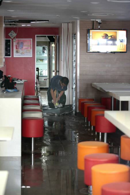 Workers clean up and repair damage to McDonald's Braddon, currently closed after a gas bottle fire at the store on Sunday night.   Photo: Jeffrey Chan