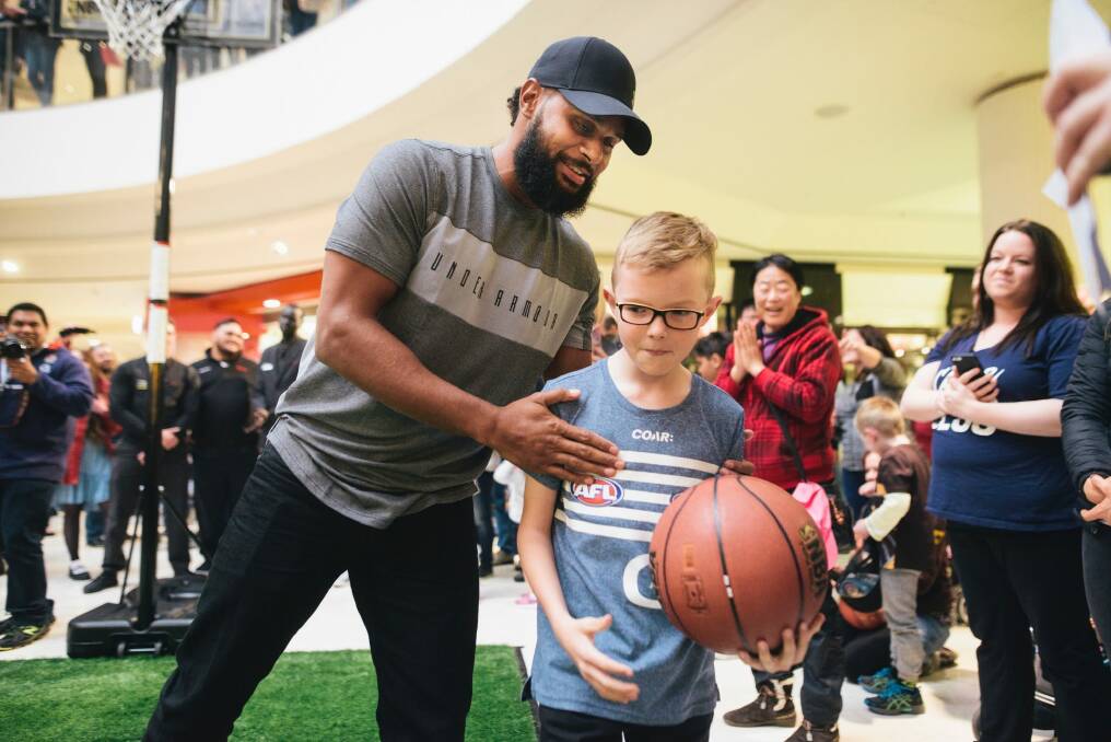 Patty Mills at Belconnen for a book signing for his new book <i>Game Day</i>. Mills congratulates Logan Harrison after Logan beat Mills in a shootout. Photo: Rohan Thomson