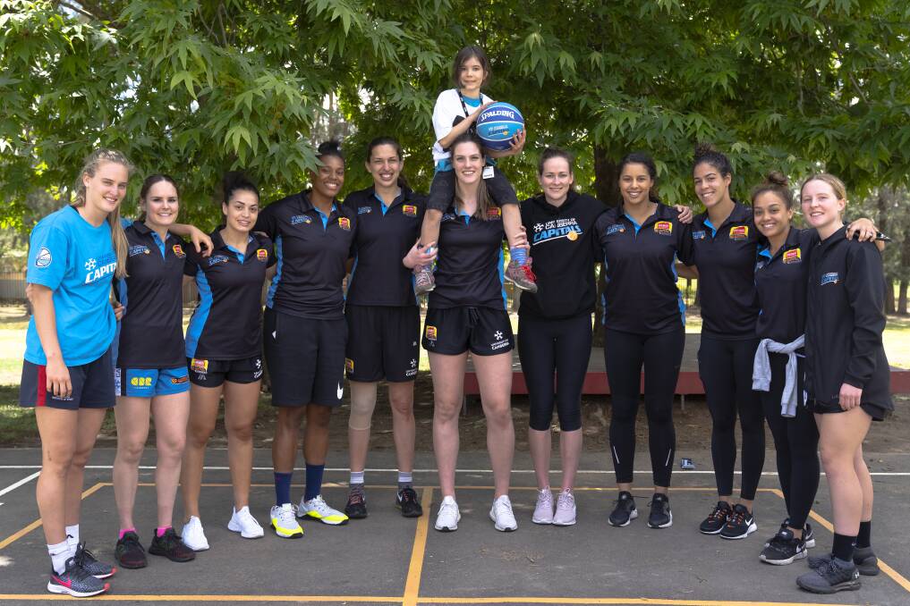 Daliah Lee (on the shoulders of Lauren Scherf) meets hers favourite team - the UC Canberra Capitals. Photo: Lawrence Atkin 
