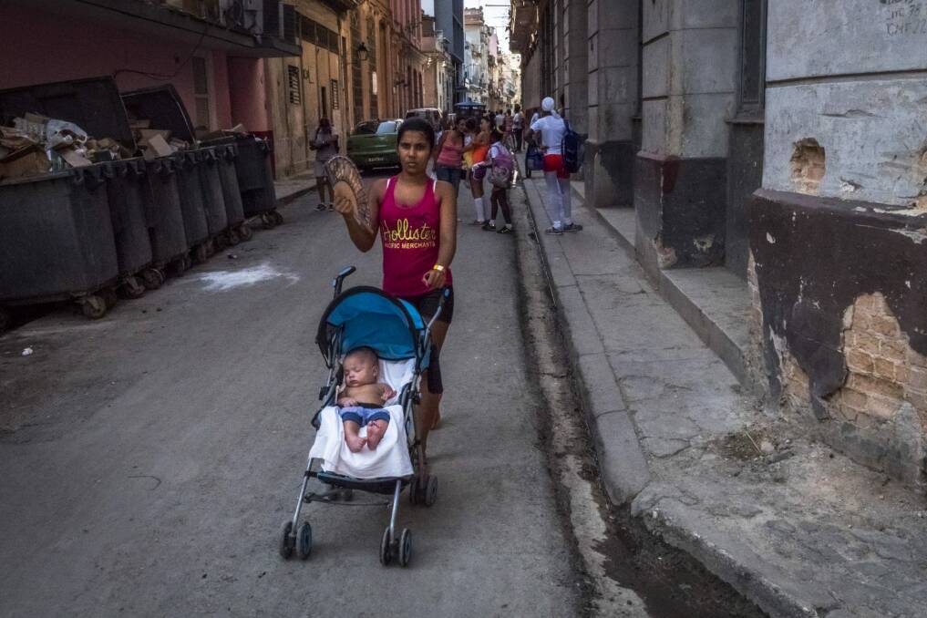 Pushing a stroller along a street in Old Havana. Few families are left untouched by the schism that followed the country's revolution. Photo: New York Times