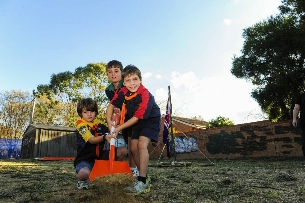 Eric Medway, nine, of Kaleen, Liam Raddatz,12, of Sutton and Alexis Cofinas, seven, of Kaleen turn the first sod on the site of the soon to be rebuilt Diamantina Scout Hall in Kaleen. Photo: Melissa Adams