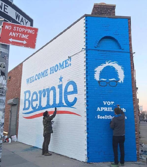 Nick Kuszyk (left) paints his NY street art welcome to the Bern.