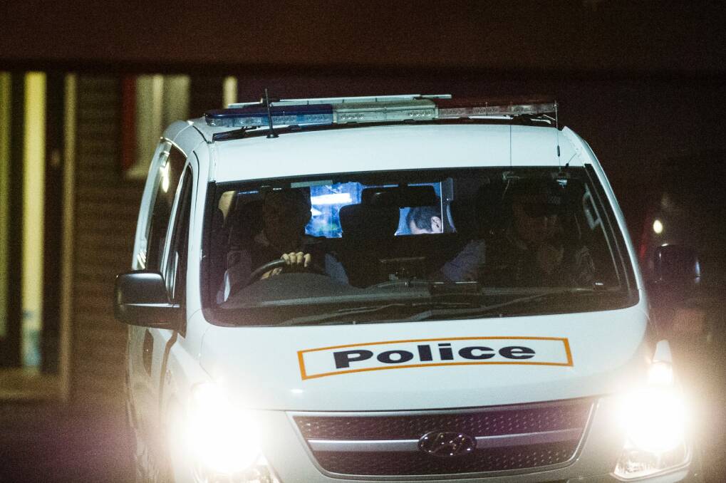 Police drive the suspect away from the unit block on Sunday.  Photo: Rohan Thomson