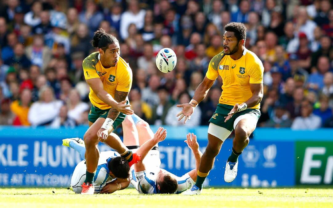 Backline movement: Joe Tomane offloads to Henry Speight during the 2015 Rugby World Cup Pool A match between Australia and Uruguay at Villa Park. Photo: Dan Mullan