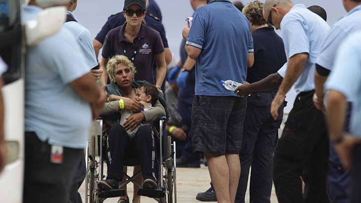 Long journey: A mother and her child are escorted by customs staff on Christmas Island on Thursday. Almost 1000 people arrived at the island this week. Photo: Wolter Peeters