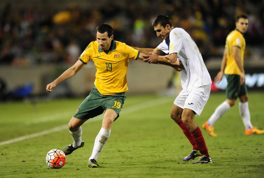 Socceroos defender Ryan McGowan and Kyrgyzstan player Amirov Ildar challenge for the ball in Thursday night's World Cup qualifier at Canberra Stadium.
 Photo: Melissa Adams