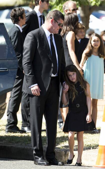 James Packer, with one of his three children, attended the funeral in Gunnedah. Photo: Media-Mode