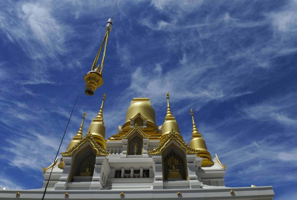 Hundreds of people attended a  ceremony at the Wat Dhammadharo Buddhist temple in Lyneham, where a crane lifted a golden tiered umbrella on to the main dome of the partly constructed pagoda. Photo: Graham Tidy