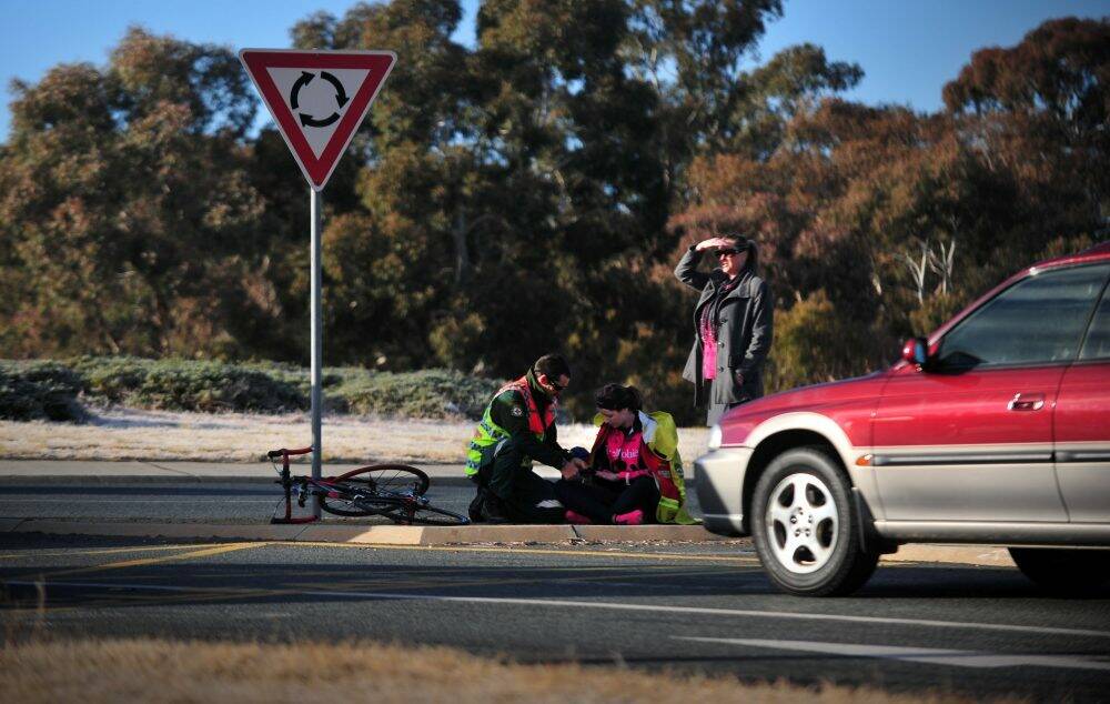 A cyclist is attended to by an ambulance officer after being hit by a vehicle at a roundabout in Kambah (file photo). Photo: Karleen Minney