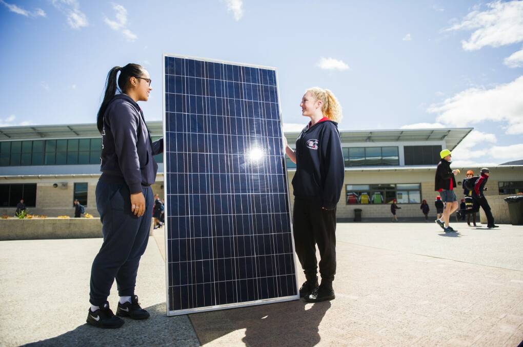Amaroo year 10 students Savannah Sithideth and Taylah Rattey with one of the solar panels to be installed at the school. Photo: Rohan Thomson