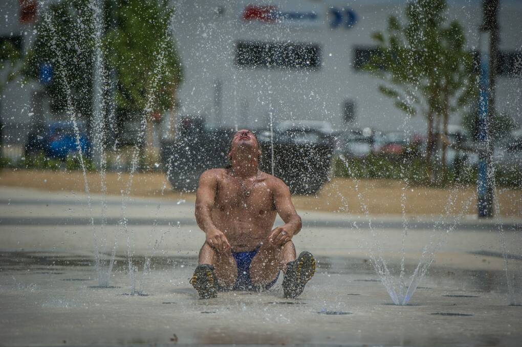 Craig Davis takes advantage of the new sprinkler fountain in Queanbeyan to cool off during the Summer hot spell. Photo: karleen minney
