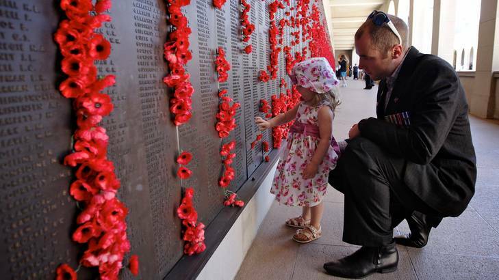 Arabella Bailey, 2, and her father, Afghanistan veteran Jamie Bailey, place a poppy on the Roll of Honour at the Remembrance Day ceremony at the Australian War Memorial in Canberra on Sunday. Photo: Alex Ellinghausen