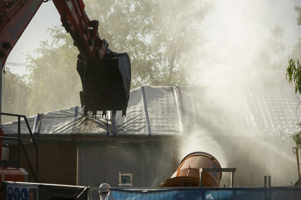 The demolition of an asbestos-contaminated home in Kaleen. A water cannon sprays a mist to keep fibres down. Photo: Jay Cronan