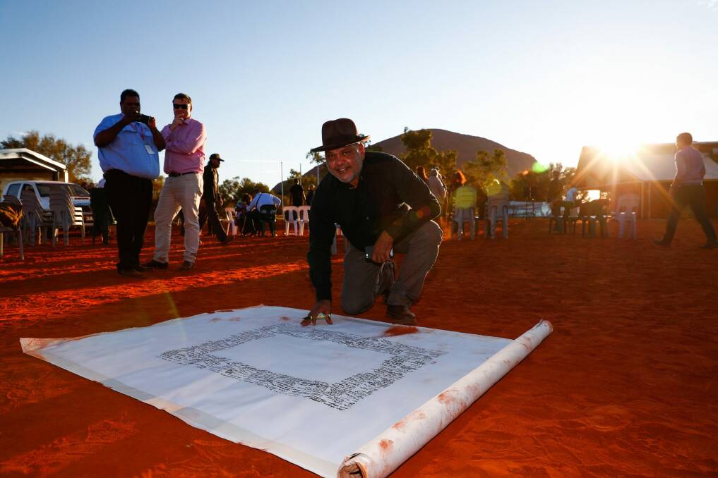 Noel Pearson signs the canvas upon which the Uluru statement was painted. The Turnbull government rejected the statement's recommendations. Photo: Alex Ellinghausen