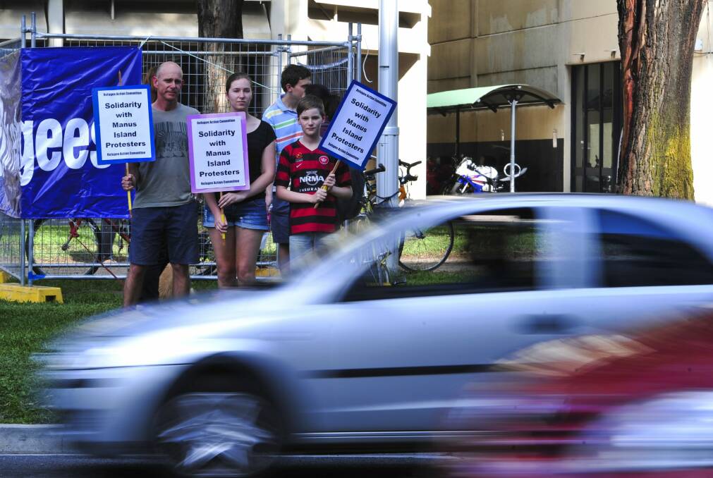 From left, Mark Stoove, of Farrer, and his children Elise,15, and Liam,11, on the corner of Northbourne Avenue and Barry Drive in Civic in solidarity with Manus Island asylum seekers. Photo: Melissa Adams